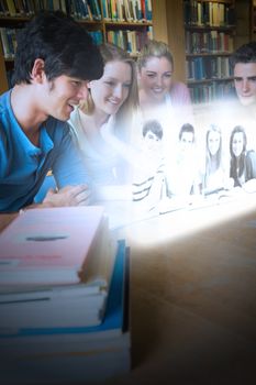 Happy college friends watching photos on futuristic interface in university library