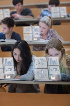 Concentrated students working on their digital tablets in lecture hall