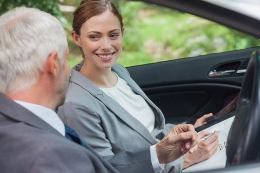 Smiling partners working together in classy car on a bright day