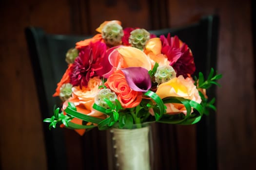 Orange, purple, green, red, bouquet sitting on a chair.