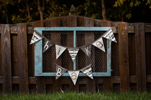 Blue vintage whiskey bar sign hanging on a fence outside for a wedding.