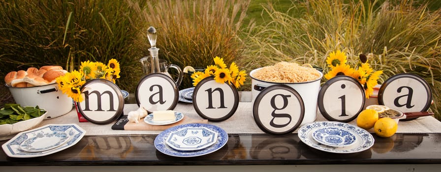 Beautiful rustic table setting with plate letters spelling out the Italian Word "Mangia."