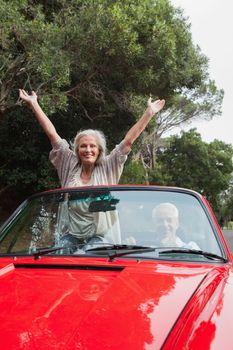 Smiling mature couple having a ride together in red convertible