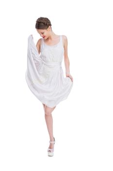 Smiling woman playing with her white summer dress on white background