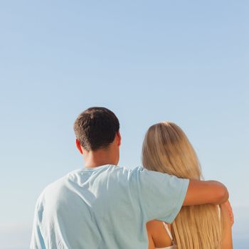 Rear view of cute couple admiring blue sky on sunny day