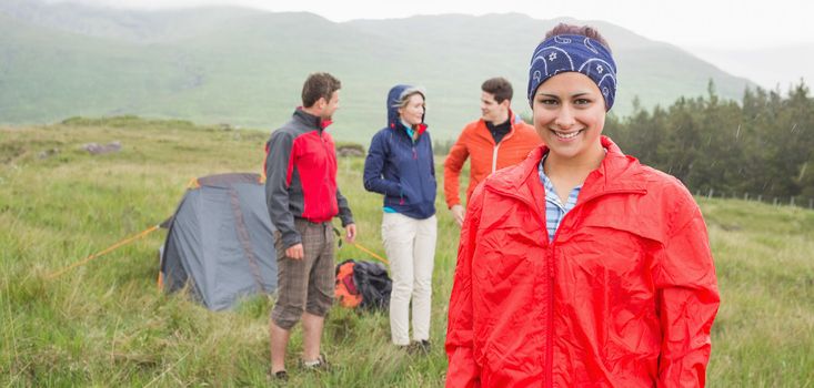 Brunette smiling at camera with friends behind her on camping trip in the countryside