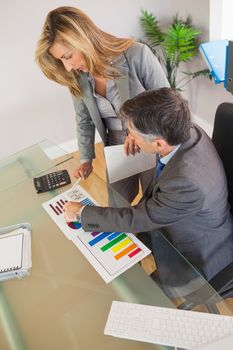 A businesswoman explaining figures to a businessman in an office