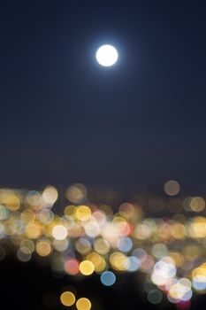 Harvest Full Moon Rise Over Blurred Defocused City Building Lights at Evening Blue Hour