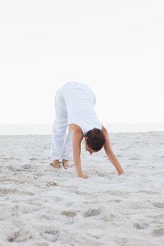 Woman doing extended triangle yoga pose at the beach