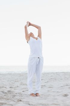 Active woman practicing yoga on the beach against the sea