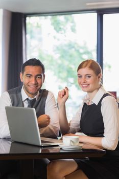 Business people working together in a cafe smiling at camera