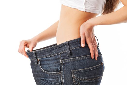 Woman showing her waist by wearing an old jeans, isolated on white