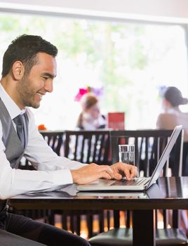 Smiling businessman looking at laptop screen in a restaurant