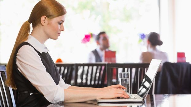 Concentrated businesswoman working on laptop in a restaurant