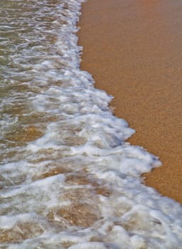 Sea coming to beach with close up on foam 