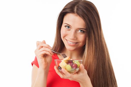 Young woman eating fruits and smiling, isolated on white