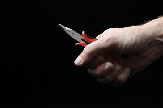 Pliers and a Hand on a Black Background