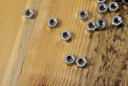 A pile of metal nuts on a wooden table