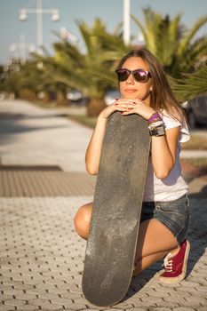 Beautiful young girl with a skateboard outdoor on summer