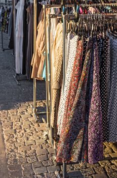 Clothes street sale. Clothing on a rack, in evening sunlight.