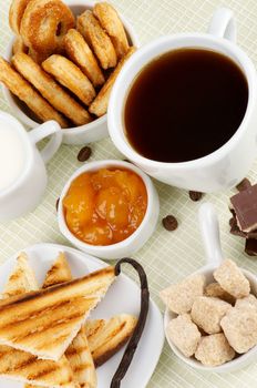 Arrangement of Coffee Cup with Chocolate, Sugar Cubes, Toasts, Apricot Jam, Milk and Puff Pastry on Checkered background