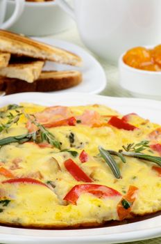 Delicious Omelet with Vegetables on Heap of Toasts, Apricot Jam and Cups background closeup