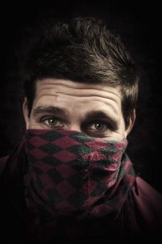 Young man with mouth covered looking at camera with aggression