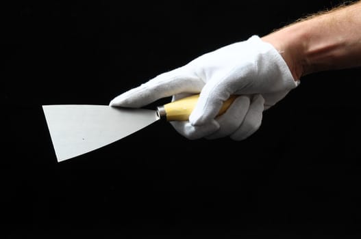 One Spatula and a Hand on a Black Background