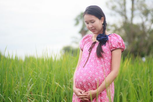 Pregnant woman on green meadow.