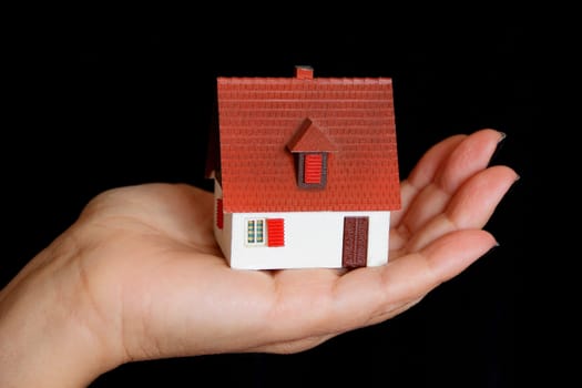 Image of dollhouse in human hand on black background