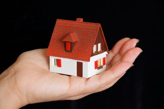 Image of dollhouse in human hand on black background
