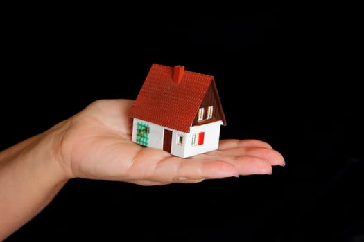 Image of dollhouse in human hand on black background