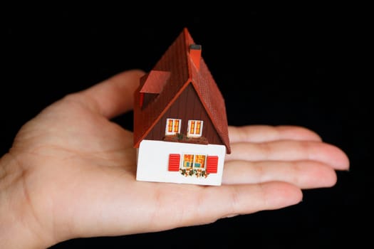 Image of dollhouse in human hand on black background