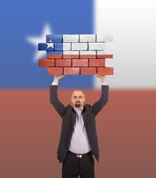 Businessman holding a large piece of a brick wall, flag of Chile, isolated on national flag