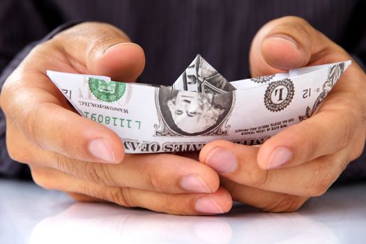 business man hand holding origami paper sailboat, money concept