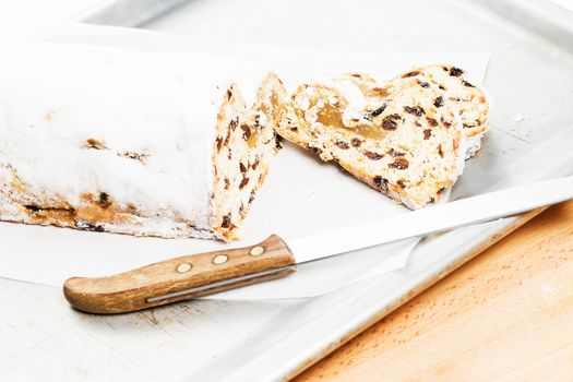 christmas stollen cake with a knife on a silver metal baking tray