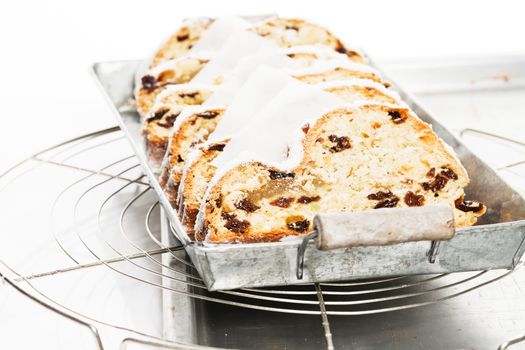 traditional christmas stollen cake on a rustic metal tray on a cooling grid