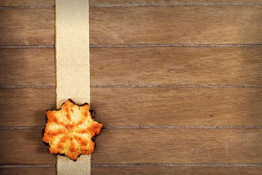 star shaped christmas coconut  cookie on a golden ribbon on wooden background with copyspace