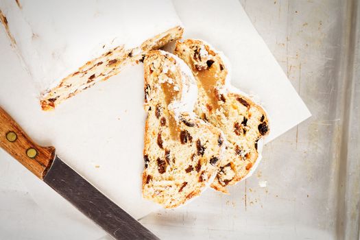 traditional german stollen cake for christmas from top on a parchment on a silver metal tray with a knife