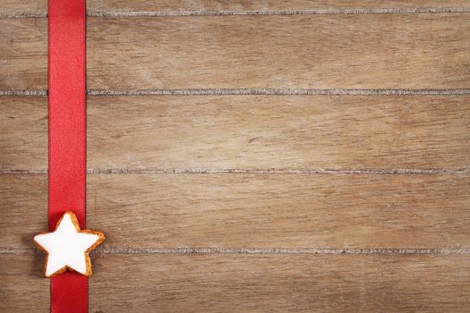 christmas cinnamon star on a red ribbon on vintage wooden background with copyspace