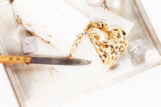 christmas stollen cake with a knife on a silver metal tray from top