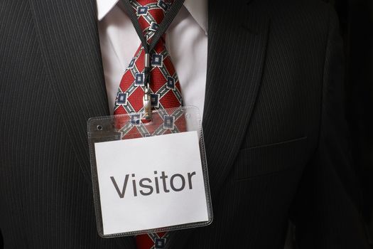 businessman wearing a visitor identification badge around his neck