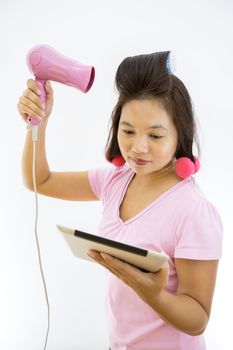 pretty young adult woman with hair dryer using tablet as mirror