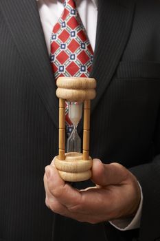 businessman holding hourglass towards camera with space for copy
