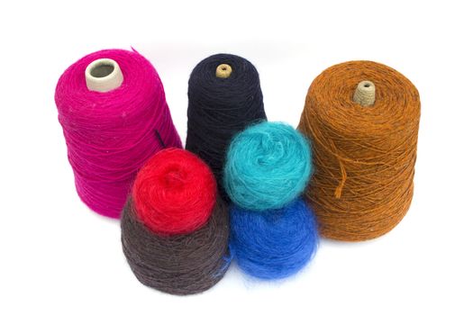 Various cones of coloured wools on a white background