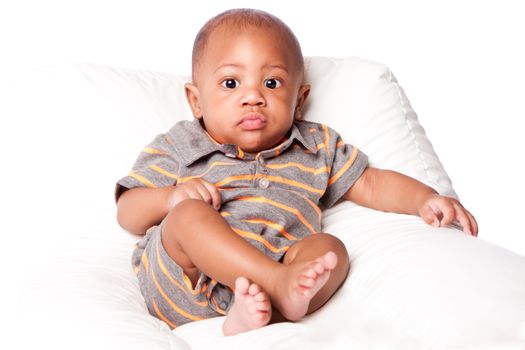 Beautiful cute adorable baby infant sitting relaxed wearing gray-orange striped onesie jumpsuit, on white.