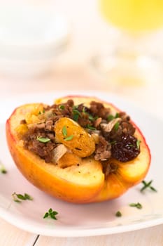 Savory baked apple filled with mincemeat, raisins, sultanas, onion and walnut, sprinkled with fresh thyme leaves on top (Selective Focus, Focus on the sultana in the front)   