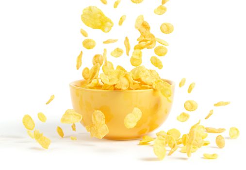 Golden cornflakes falling into the breakfast bowl