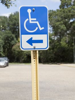 Blue handicapped parking sign in almost empty parking lot