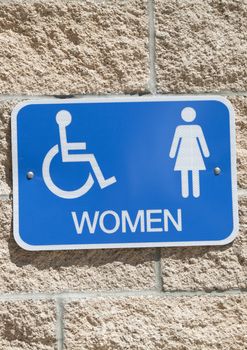 Blue women's restroom sign on brick wall
